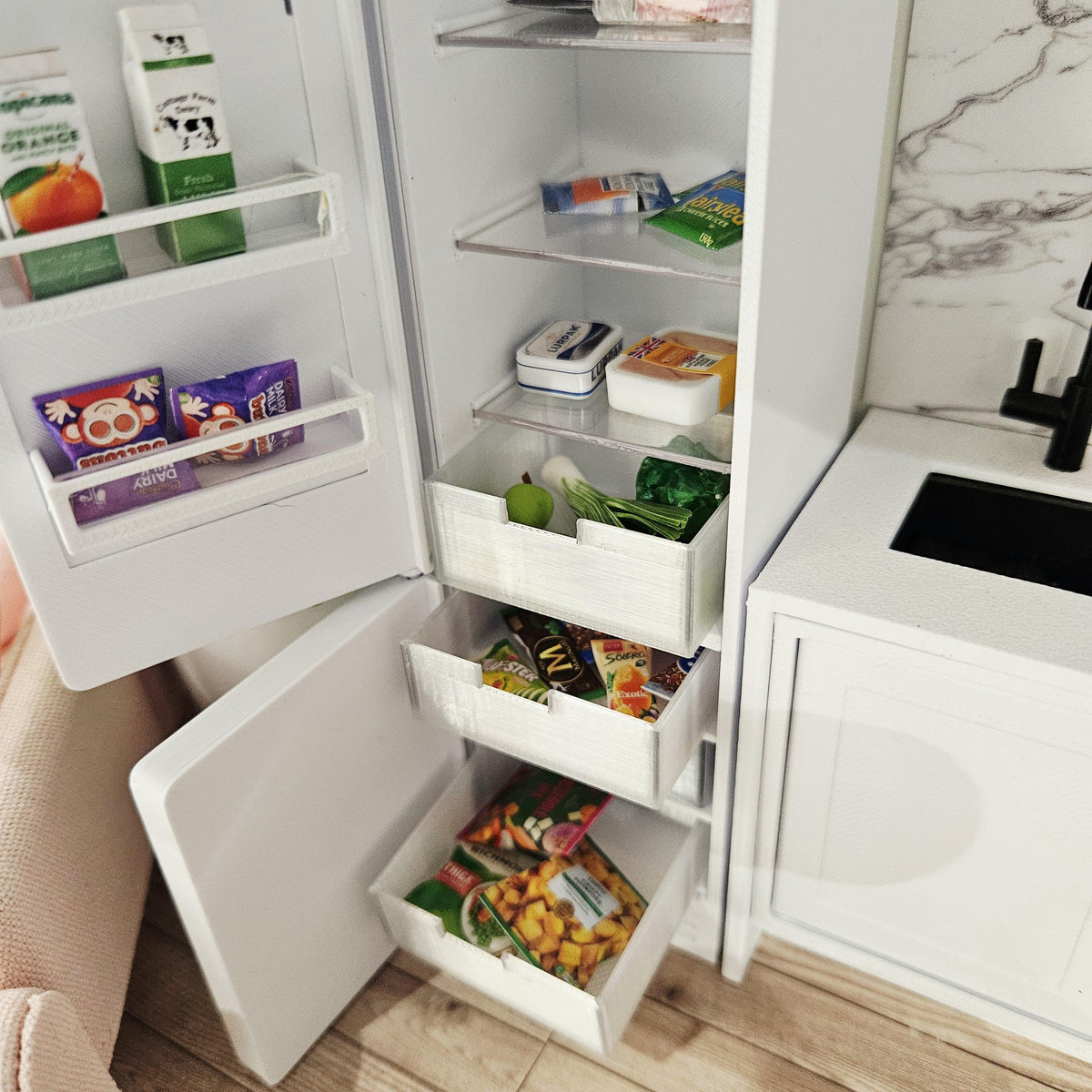 Detail of the fridge door shelves, salad drawer and open freezer drawers; miniature food is not included