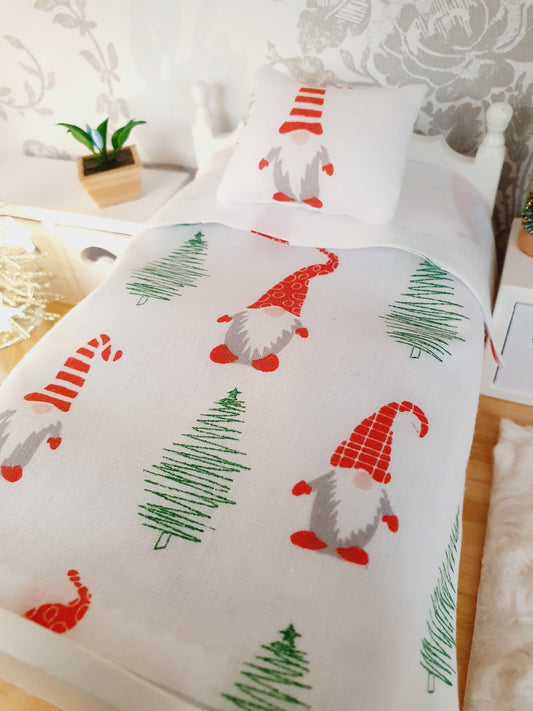Dollhouse Christmas 4-piece bedding set, 1:12 scale. Includes festive gnome bed cover (19cm x 15cm), mattress (19cm x 15cm), large check cushion (5cm x 5cm), and small scatter cushion (3.5cm x 3.5cm). Perfect miniature holiday decor for doll beds