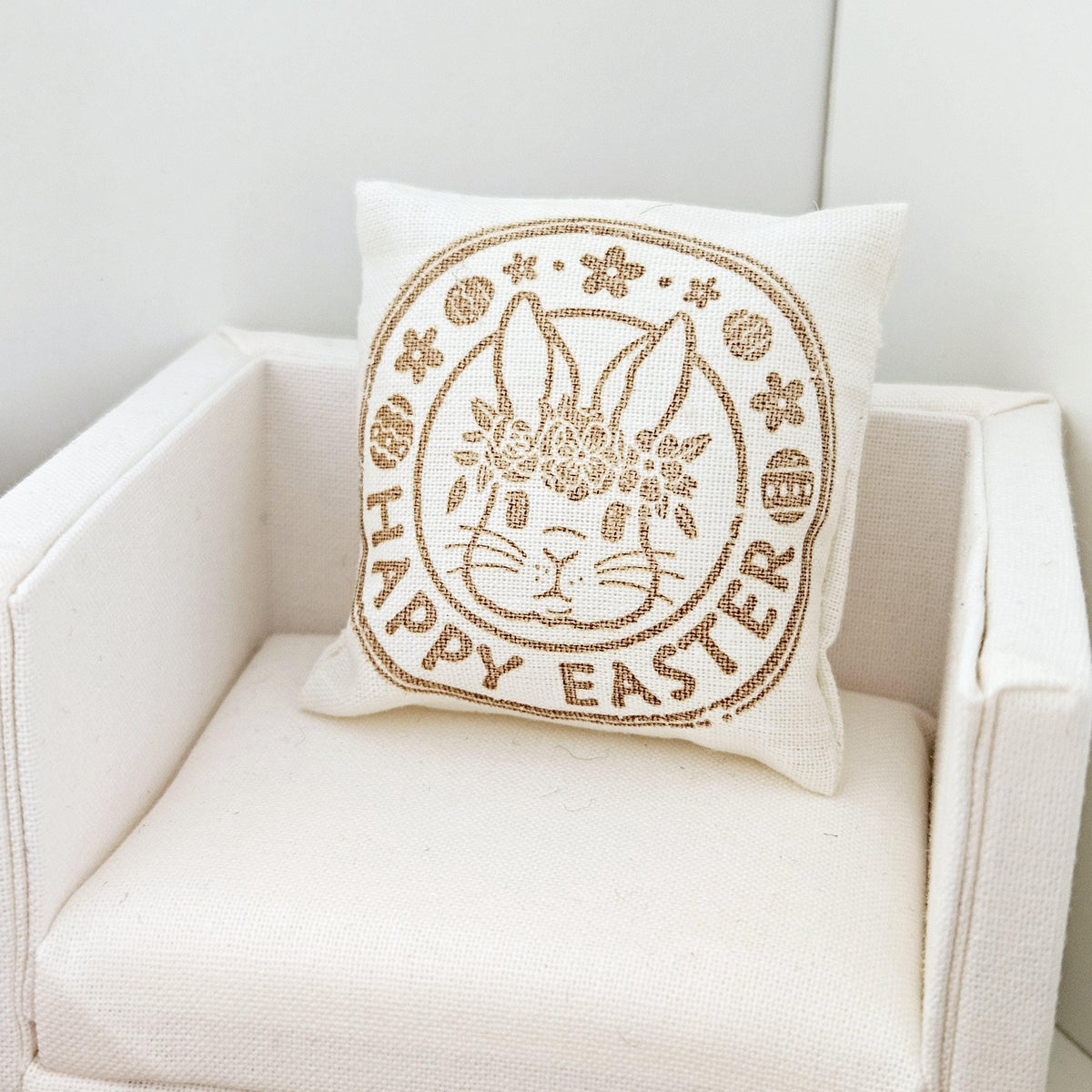 dollhouse cushion, 4cm, cream with gold writing with happy easter and a bunny face in a circle on a square cushion, 12th scale, miniature cushion