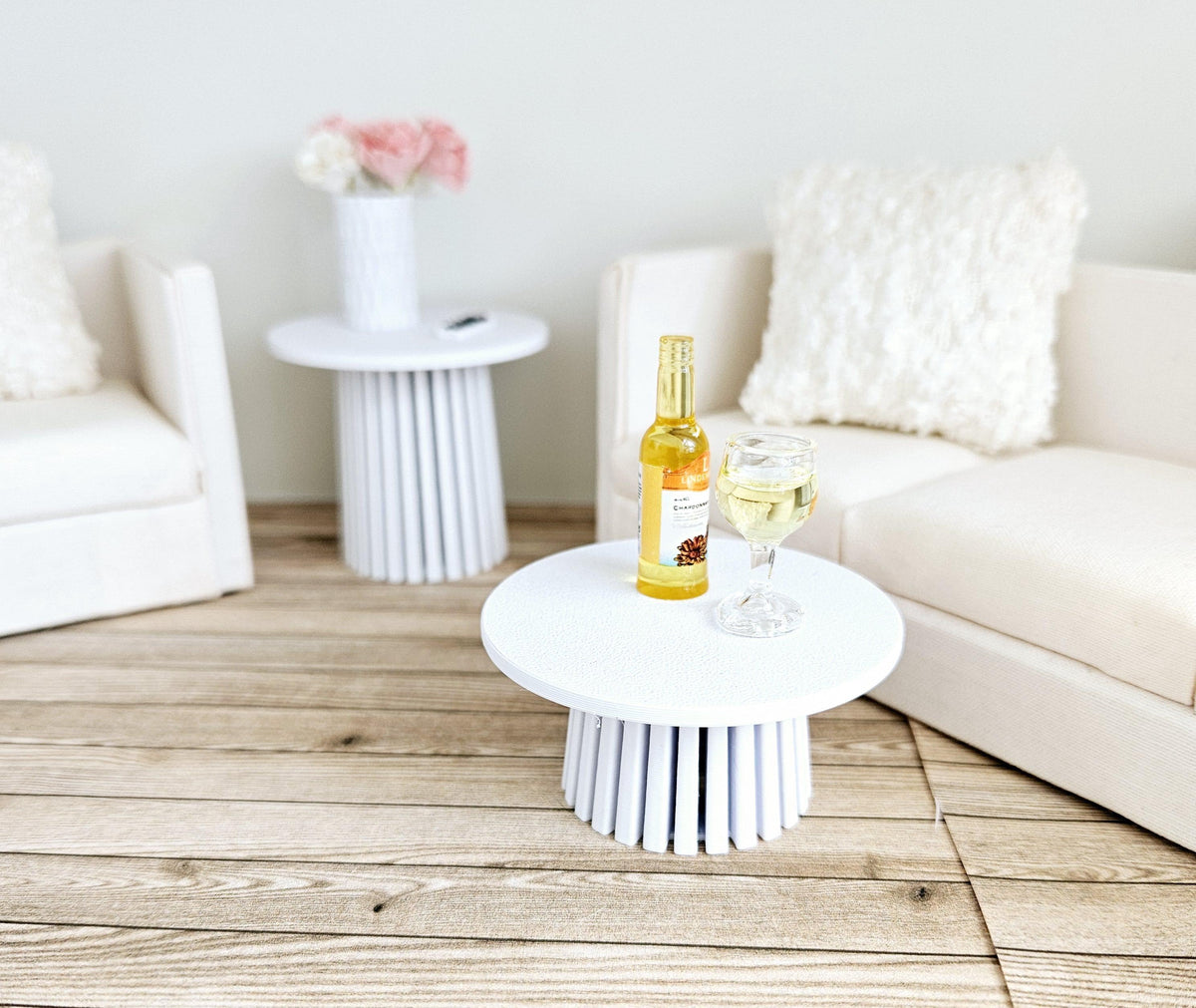 May include: Two white side tables with a white sofa and a bottle of wine and a glass of wine on one of the tables.