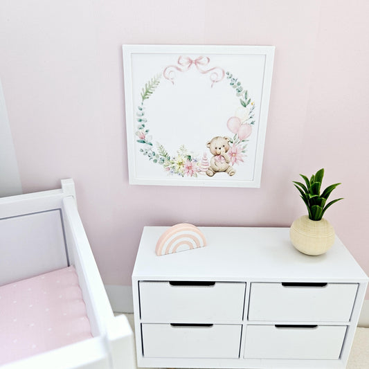 May include: White chest of drawers with four drawers, a pink and white rainbow wooden toy, and a framed watercolour print of a teddy bear holding balloons in a floral wreath.