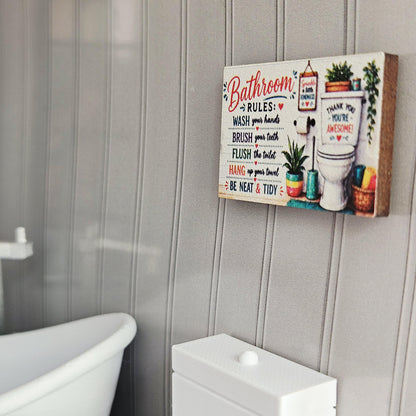 May include: A rectangular wooden sign with the words "Bathroom Rules" in red script. The sign includes instructions like "Wash your hands" and "Brush your teeth", along with a picture of a toilet and plants. The sign is mounted on a grey wall.