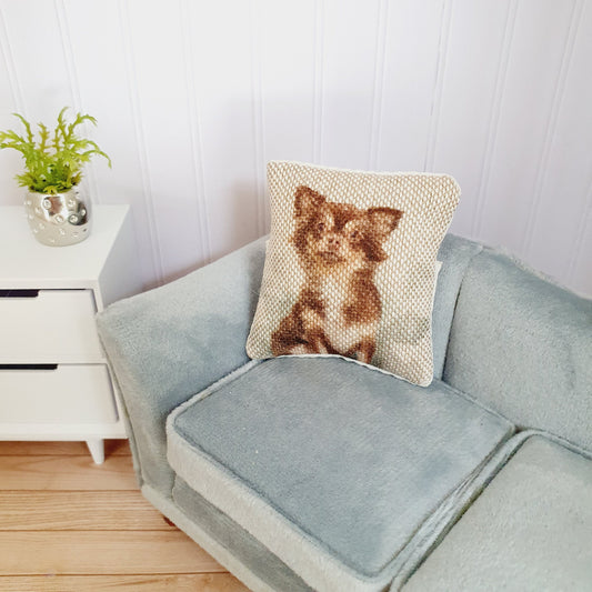 May include: A light blue sofa with a beige cushion featuring a brown and white chihuahua.