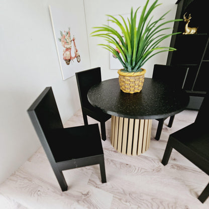 May include: A black dining table set with four black chairs and a round black granite tabletop. The table has a wooden base with a slatted design. A potted green plant sits in the centre of the table.