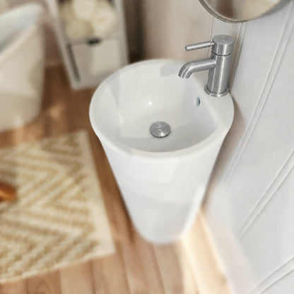 Close-up of white 1:12 scale bathroom sink with silver tap and matching plug