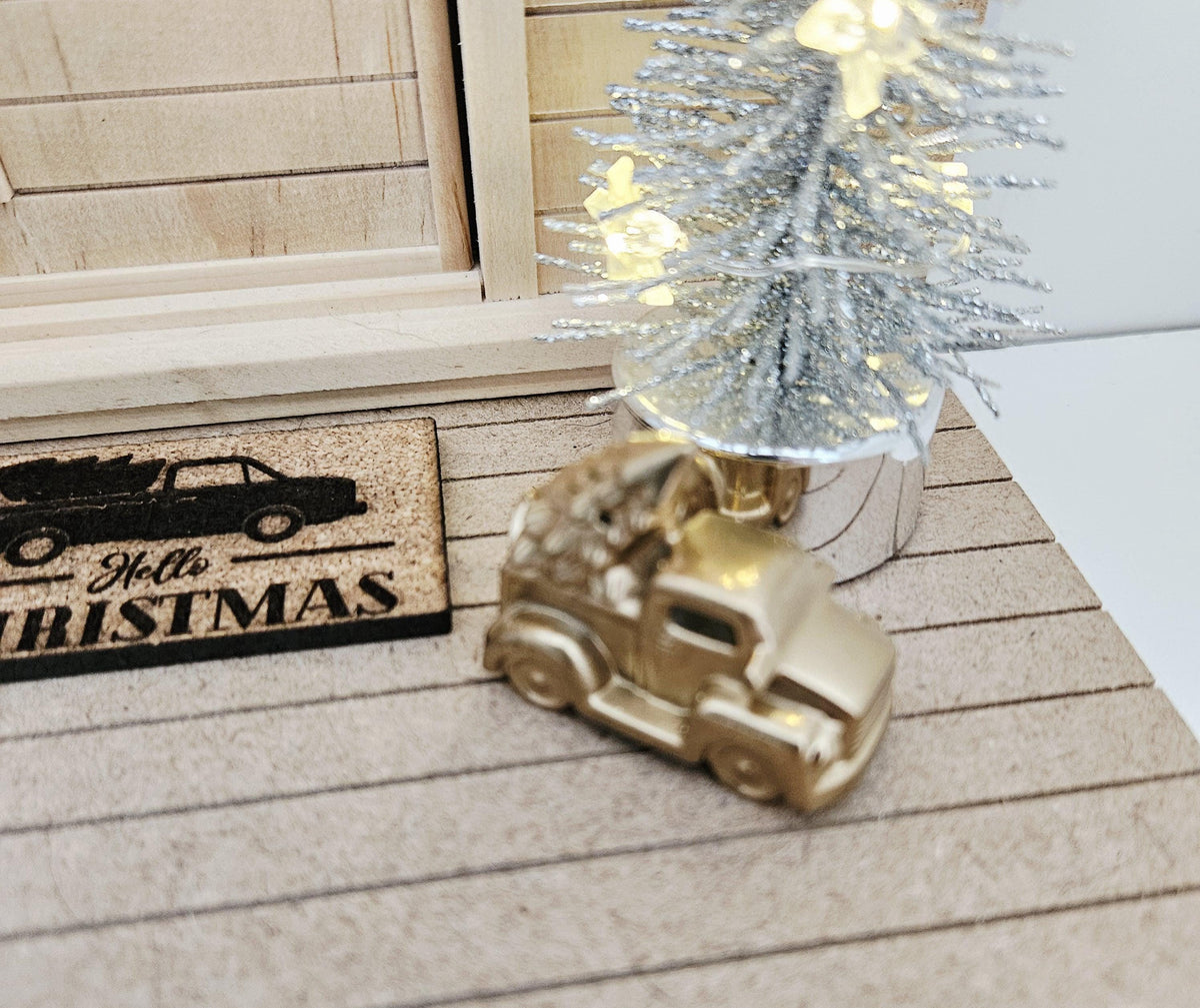 Gold pickup truck carrying a Christmas tree on a dolls house porch, 1:12 scale