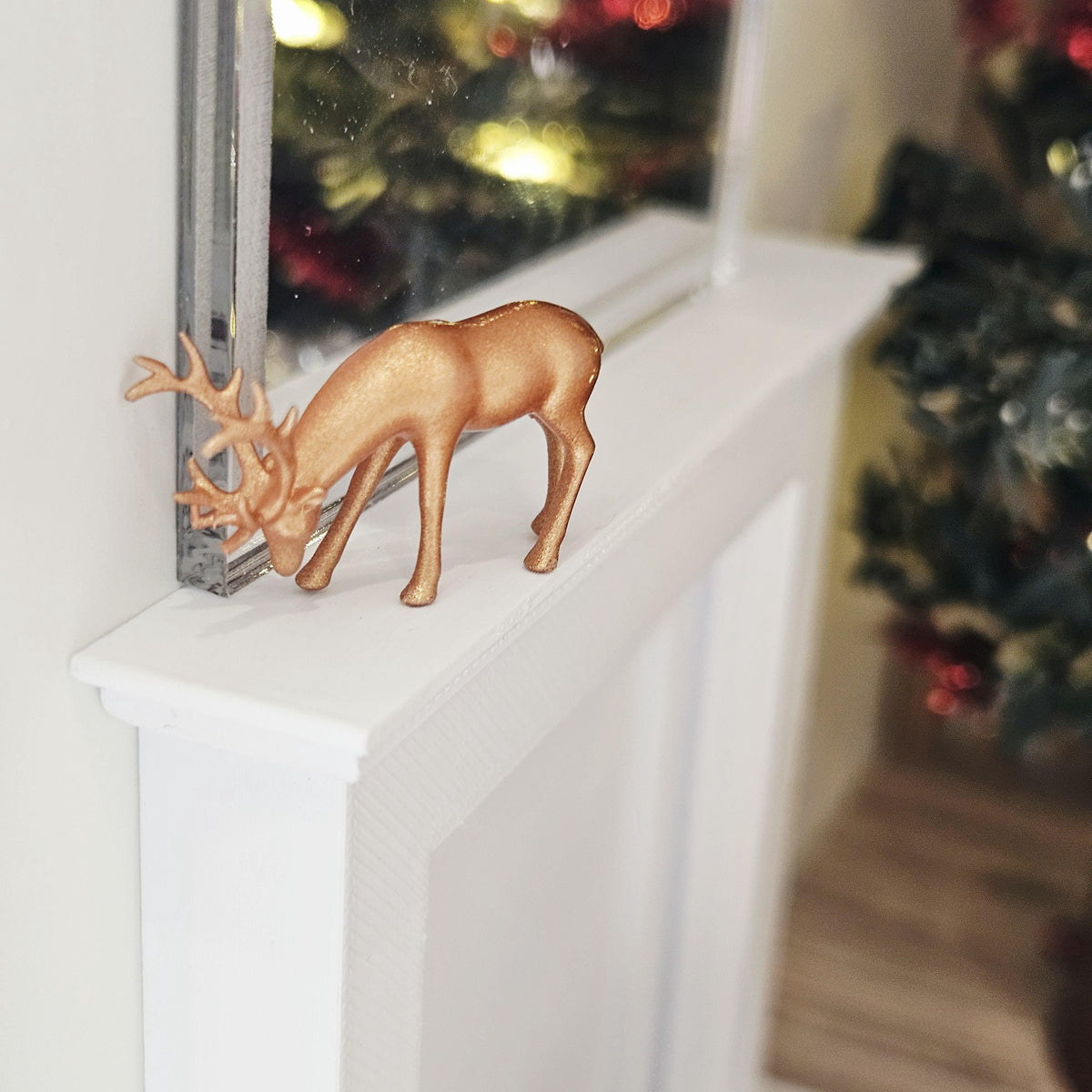 Copper Christmas reindeer ornament with lowered head and antlers on a dolls house mantelpiece, 1:12 scale