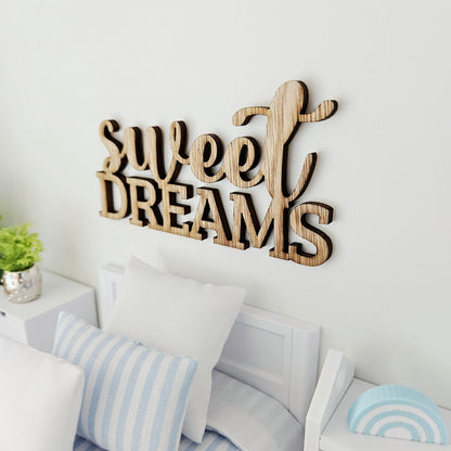 Angled view of the Sweet Dreams sign above a miniature bed, showing visible grain, dark edges and contrasting lettering styles.