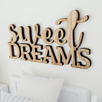 Close angled view of the Sweet Dreams sign showing grain, dark letter edges and script lettering above bold capitals.