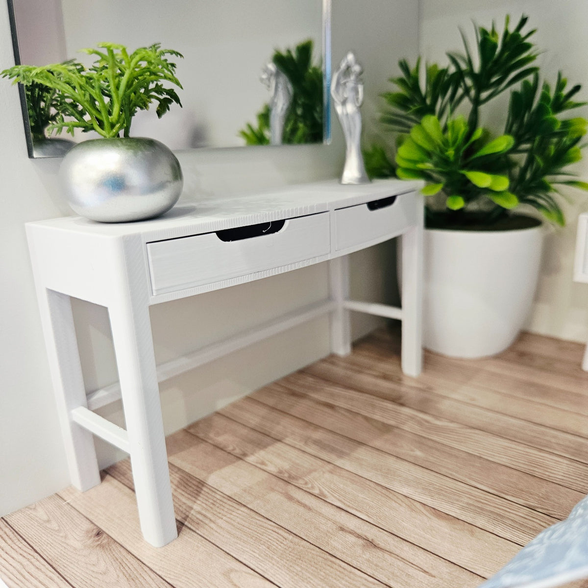 White miniature dressing table styled beneath a wall mirror with a silver planter and ornament
