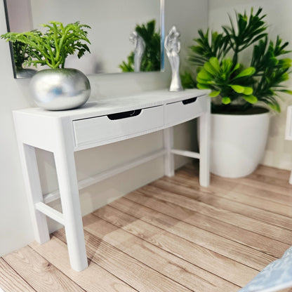 White miniature dressing table styled beneath a wall mirror with a silver planter and ornament