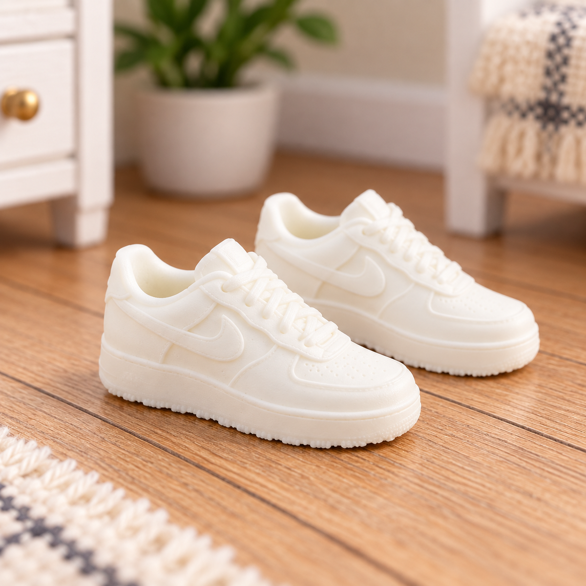Close-up of a pair of white 1:12 scale miniature trainers showing laces and sole detail