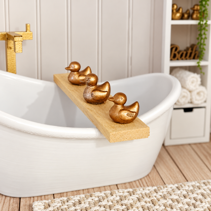 Angled close-up of a wooden dolls house bath board with three miniature gold ducks
