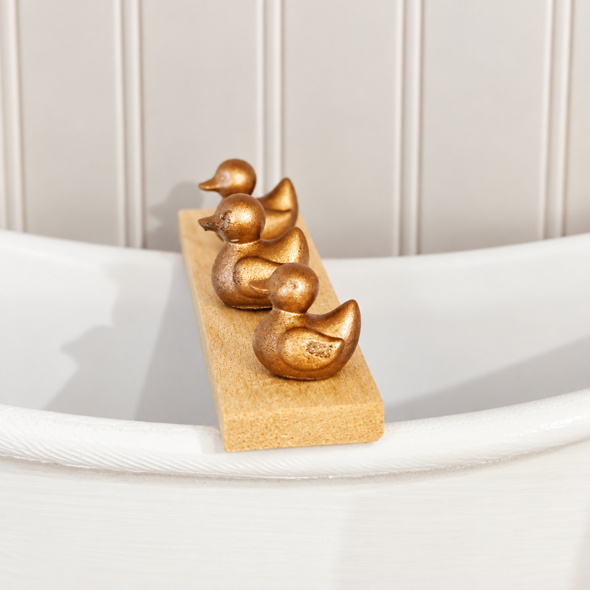 Close-up of three miniature gold ducks on a wooden dolls house bath board